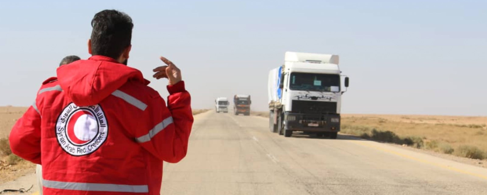 En frivillig i Røde Halvmåne dirigerer konvoien av lastebiler med nødhjelp som ankommer Rukban. 