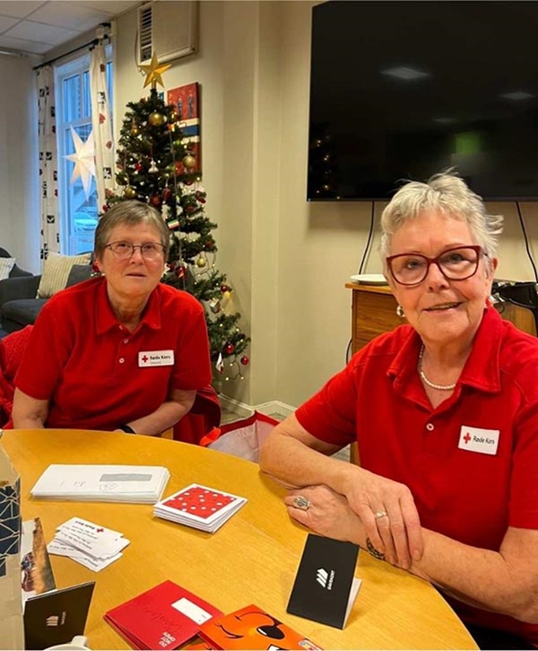 To kvinner i Røde Kors-skjorte smiler til kamera.