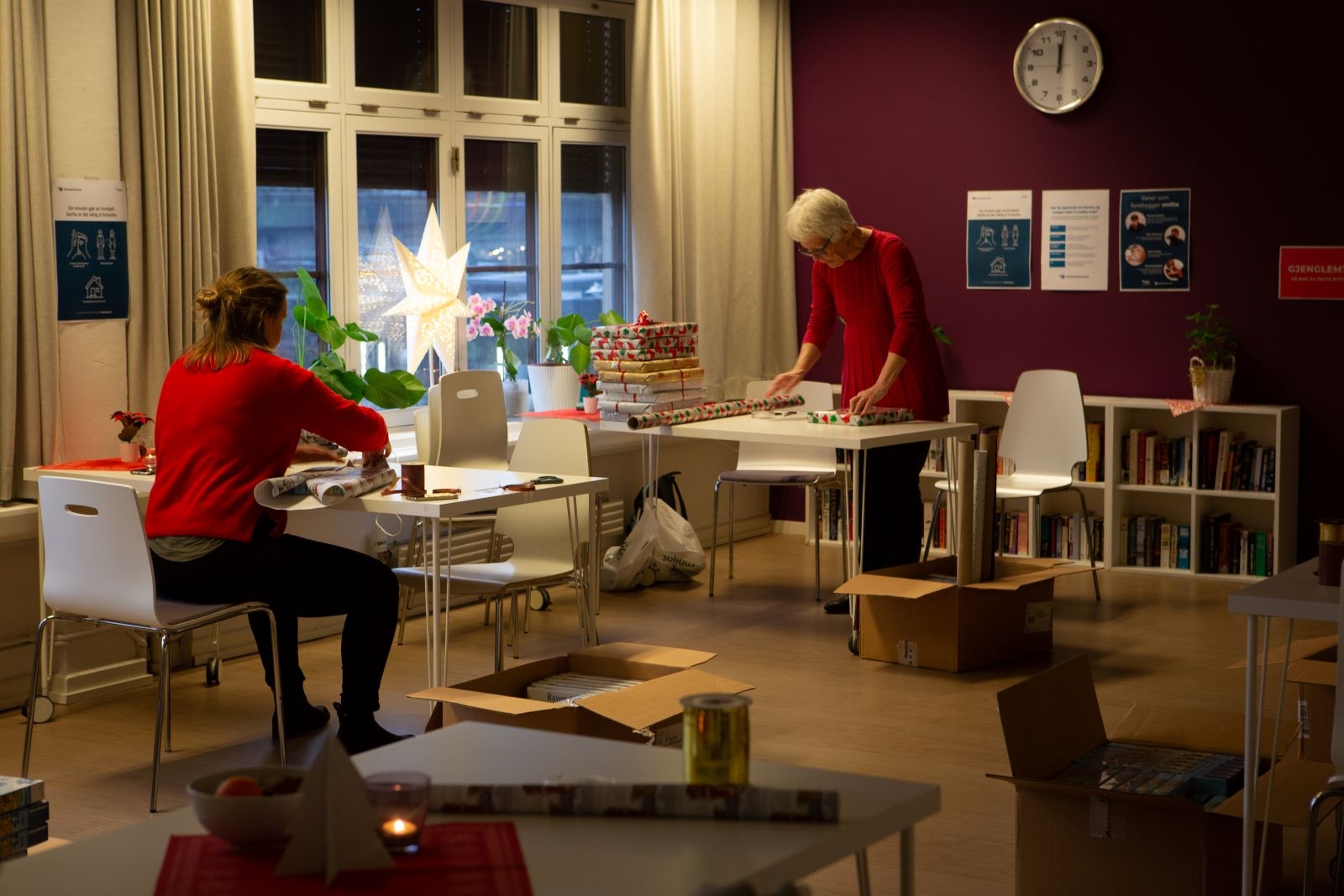 To personer pakker inn julegaver med koselig julestemning rundt