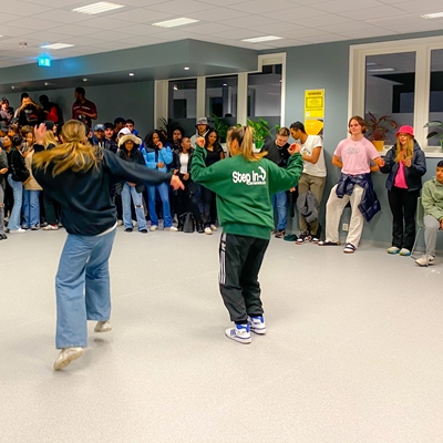 En gjeng undommer står i ring og ser på ungdom som danser