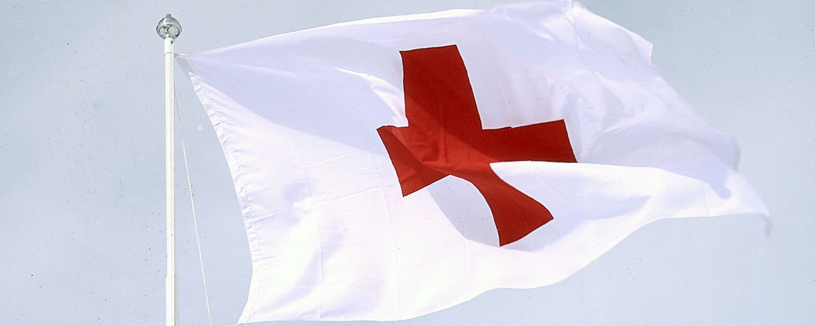 Hvitt flagg med et rødt kors vaier i vinden