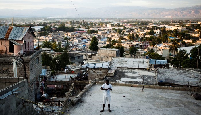 En mann står på en høyde med utsikt over en by.