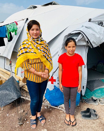 To jenter utenfor telt i flyktningleir i Hellas
