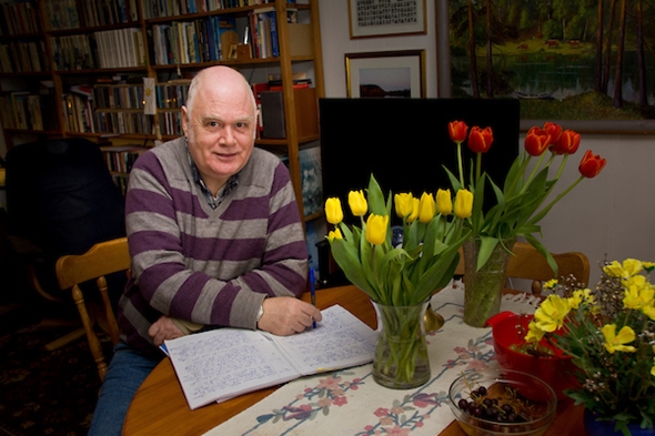 En mann sitter ved et bord og skriver 