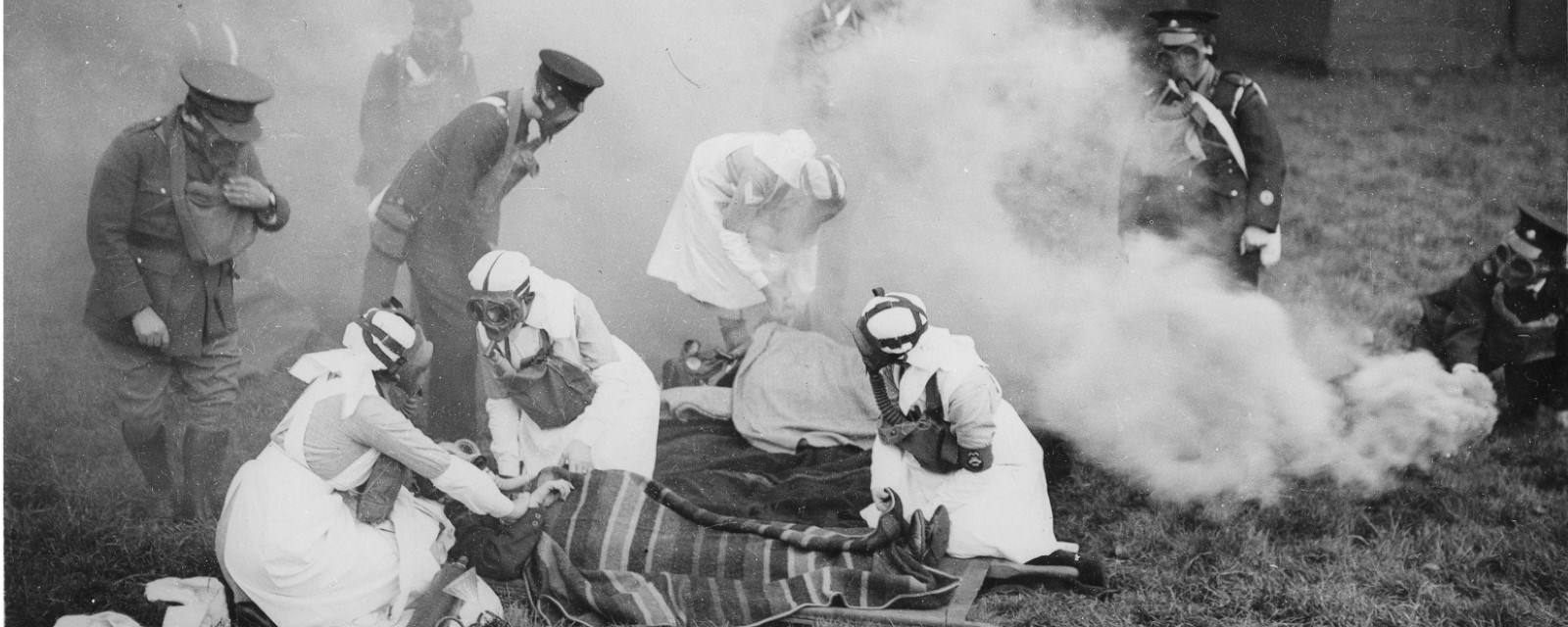Helsepersonell og soldater iført gassmasker står bøyd over pasienter under en øvelse fra Storbritannia på 30-tallet