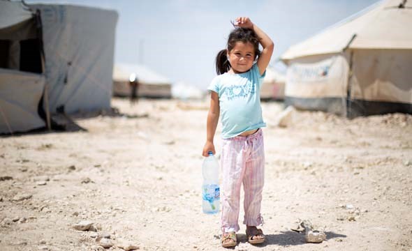 Liten jente står alene foran telt i flyktningleir i Syria