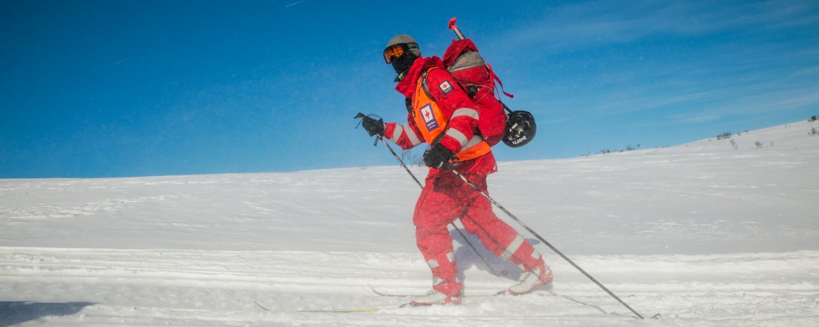 Fotografiet viser en skigåer i Røde Kors-uniform som er godt kledd for å takle kulde.