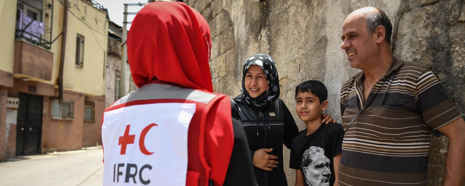 En kvinne fra Tyrkisk Røde Halvmåne snakker med en kvinne, mann og en gutt