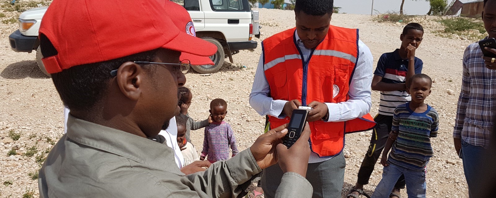 En person med Røde Kors caps holder en mobiltelefon
