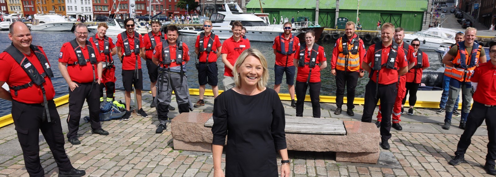 Justisminister Monica Mæland står foran mannskap fra Røde Kors hjelpekorps på bryggen i Bergen