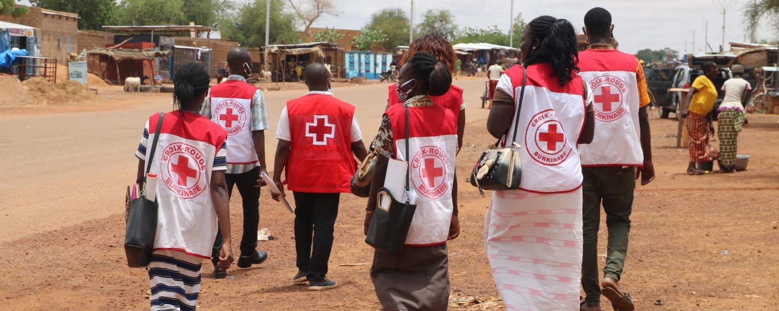 Syv personer med Røde Kors-vest går bortover en gate