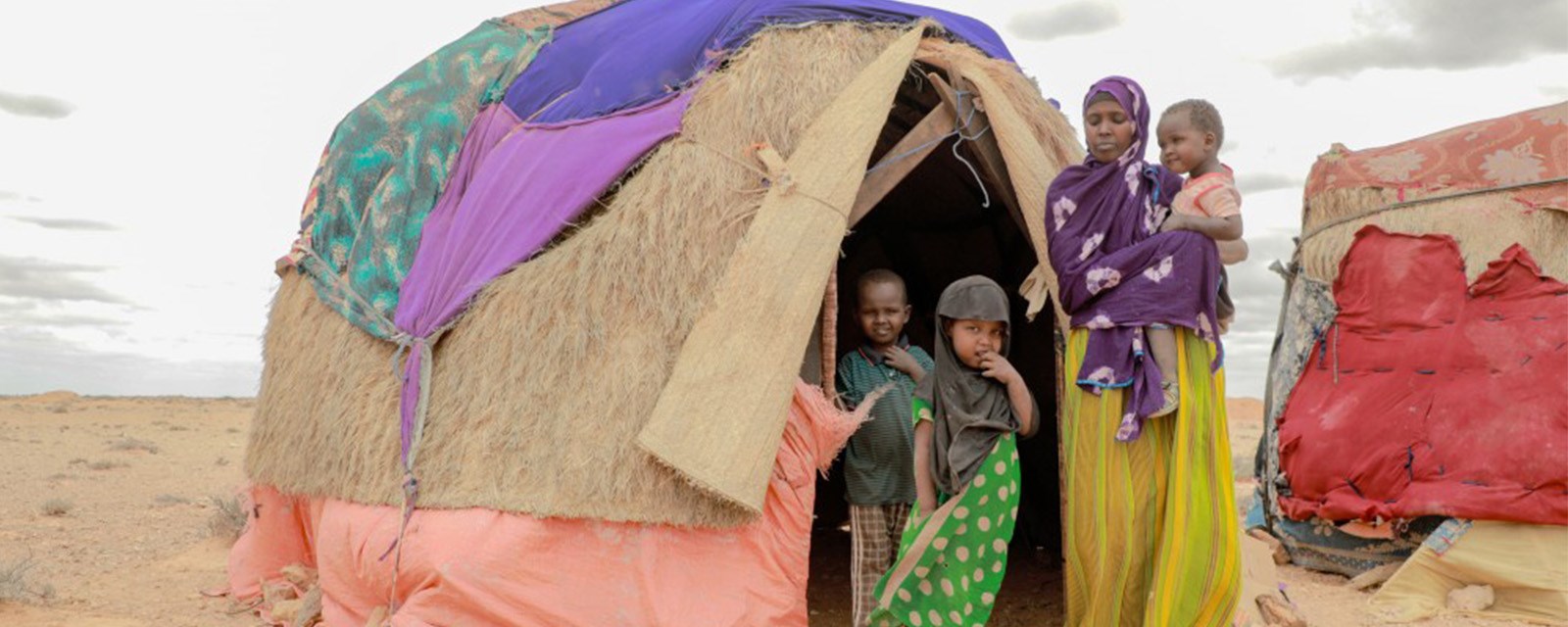 Familie utenfor hjemmet sitt i Somalia, et telt på tørre sletter.