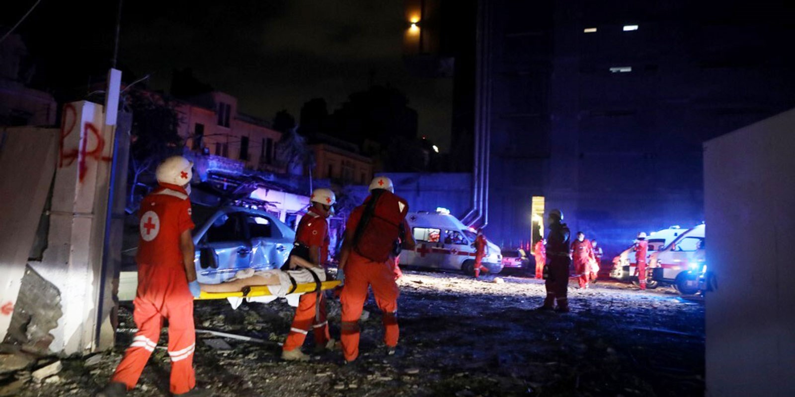Nattbilde av Røde Kors mannskap bærer bort skadde etter eksplosjon i Beirut