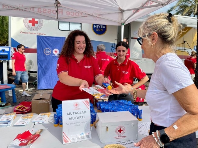 To damer deler ut solkrem og informasjon om ekstremvarme.