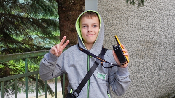 Gutt viser victory tegn og holder en satelittelefon