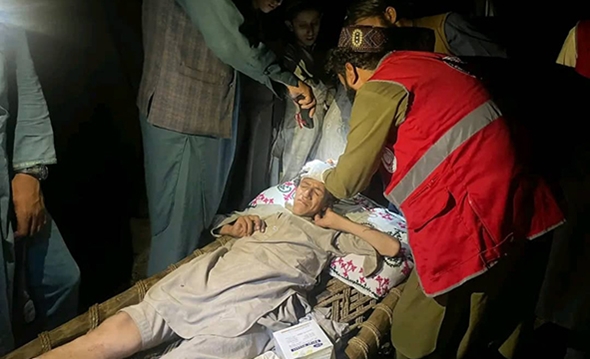 Leger undersøker en mann som er skadet i jordskjelvet.