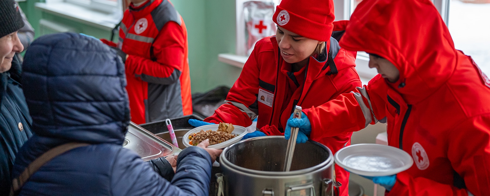 Frivillige deler ut suppe i et varmetelt.