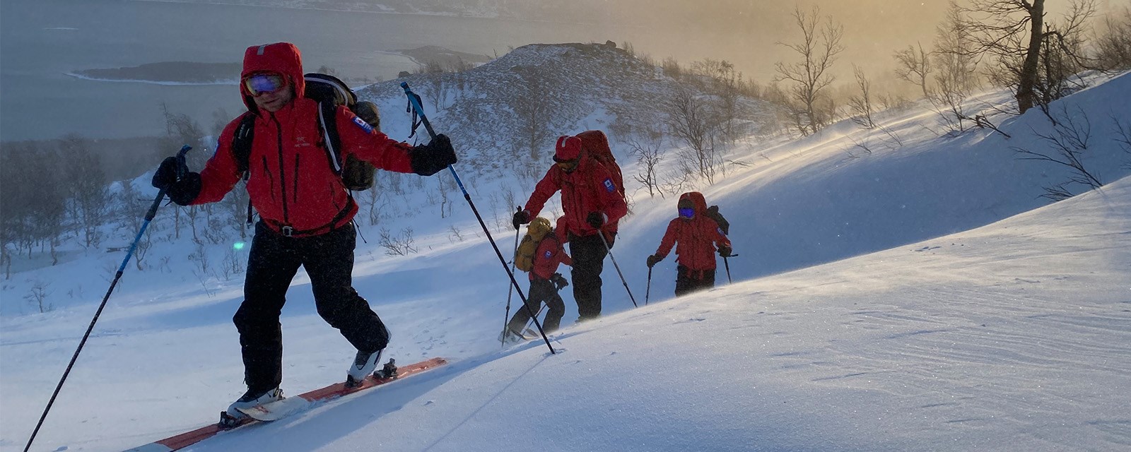 Mennesker på vei oppover fjellet med ski på beina.