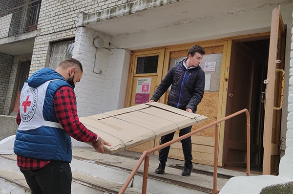 To menn bærer utstyr til en skole i det østlige Ukraina.