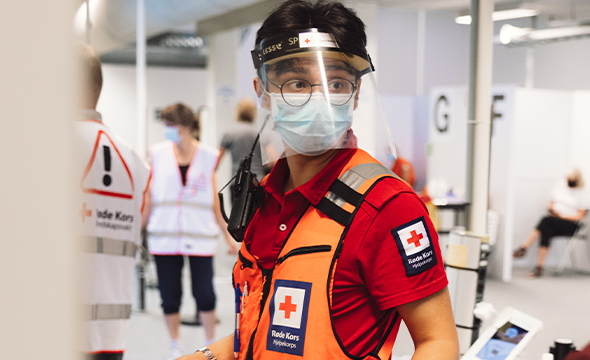 En mann med Røde Kors-uniform med smittevernsutstyr.