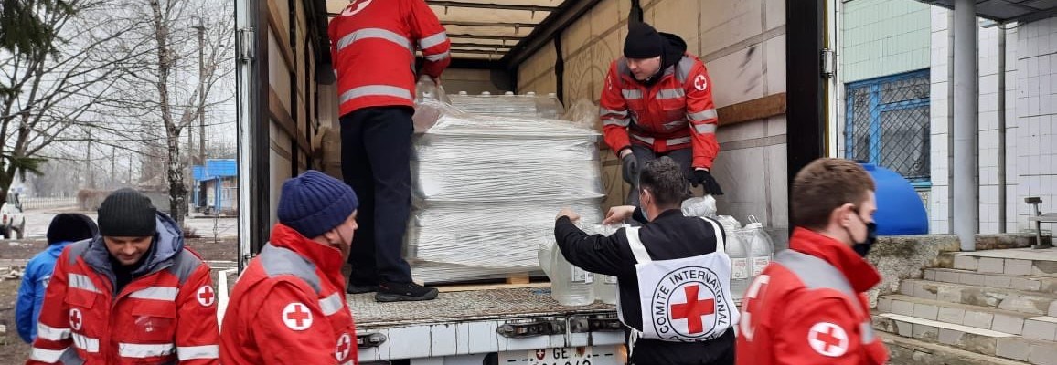 Syv frivillige fra Røde Kors bærer ut dunker med vann fra en lastebil.