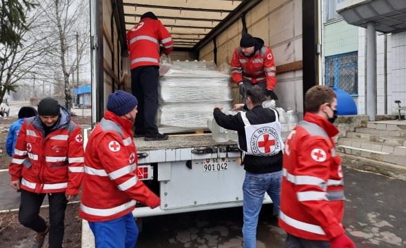 Syv frivillige fra Røde Kors bærer ut vann fra en lastebil