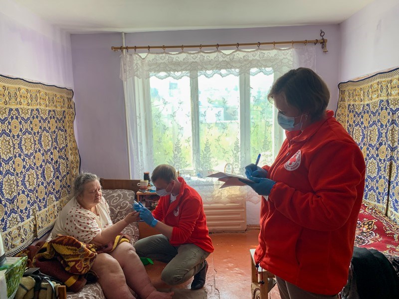 En eldre kvinne med helseproblemer blir undersøkt hjemme av personell fra Ukraina Røde Kors.