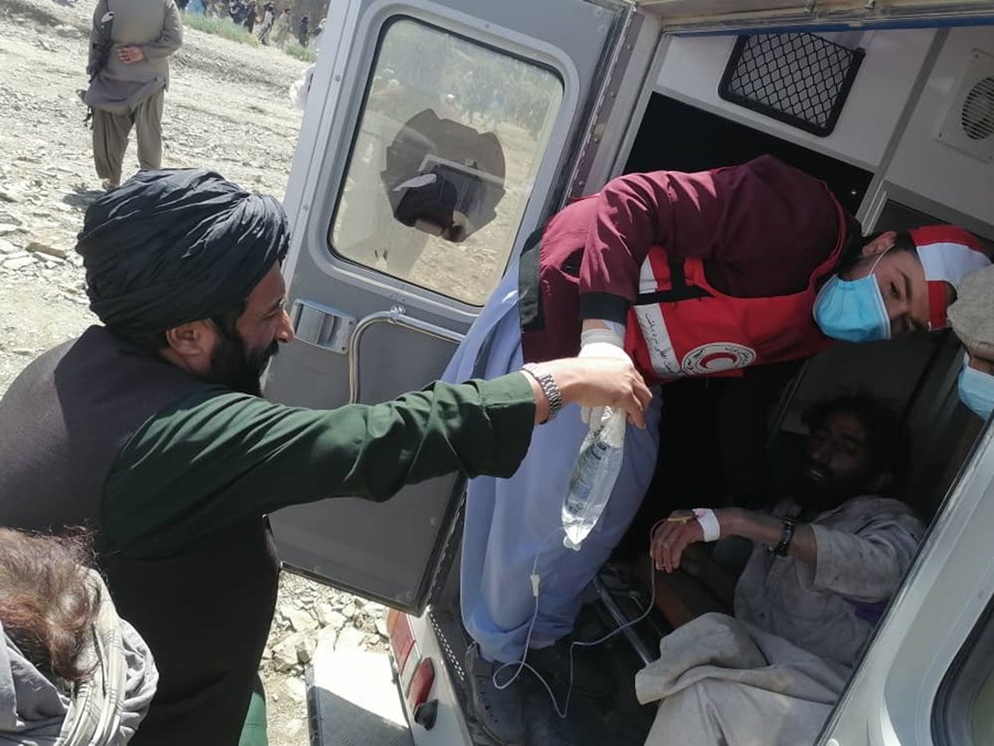 To menn fra Afgansk Røde Halvmåne hjelper en mann inn i en bil