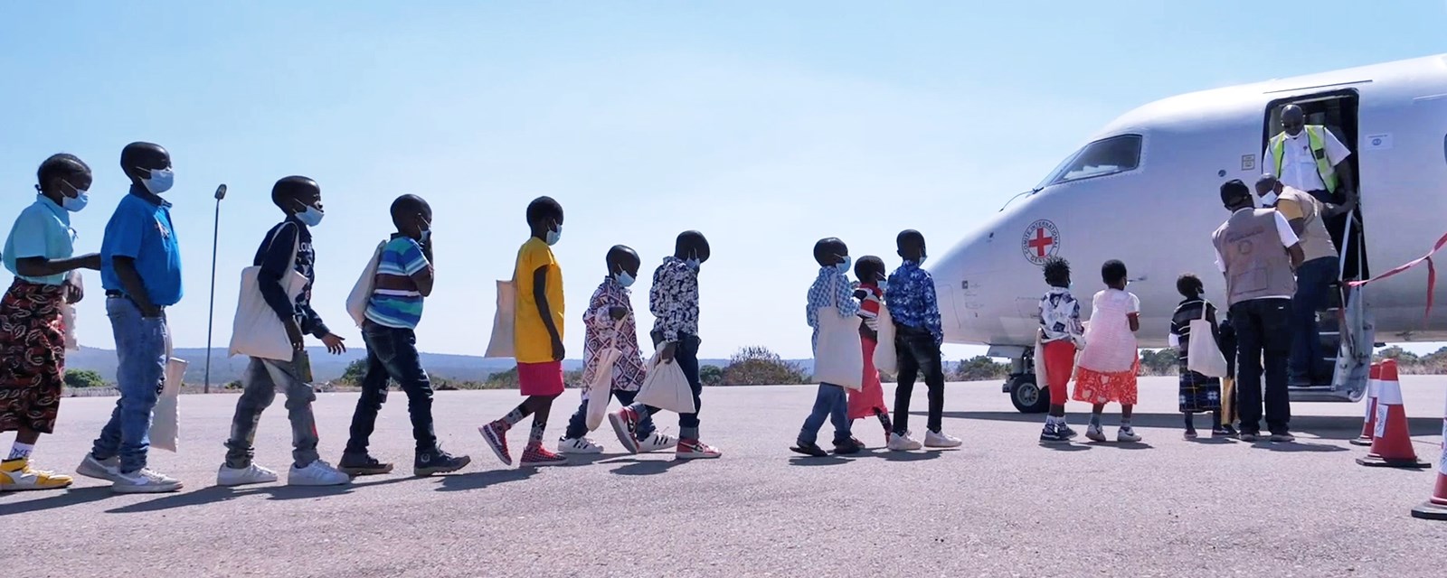 Barn på vei inn i Røde Kors-fly for å bli gjenforent med sine familier