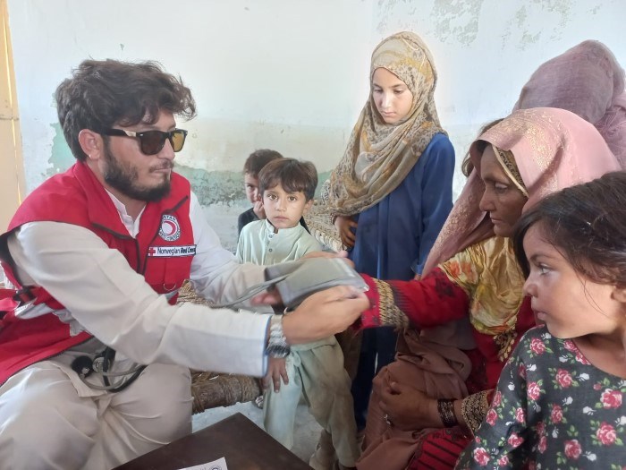 En mann fra Pakistan Røde Halvmåne tar blodtrykket på en kvinne