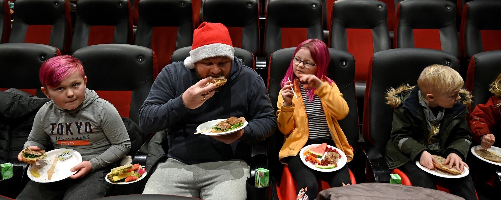 Tre barn og en voksen spiser i en kinosal