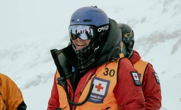 En mann fra Hjelpekorpset med hjelm og slalombriller smiler