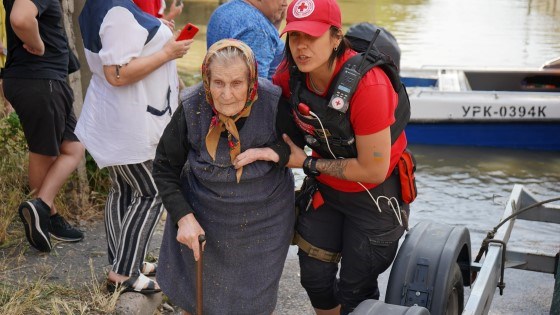 Frivillig fra Røde Kors hjelper en eldre kvinne som har blitt evakuert ut av en båt.