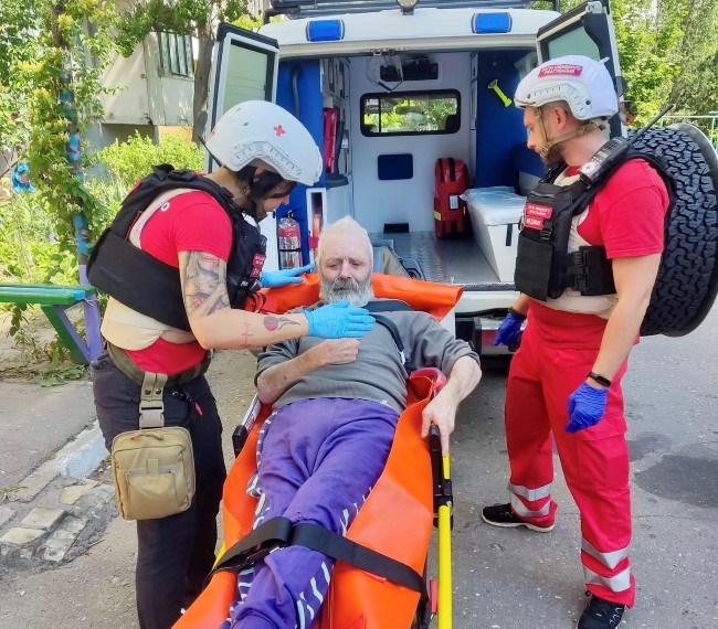 Frivillige fra Røde Kors evakuerer en eldre mann som ligger på en båre