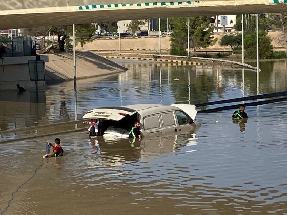 Redningsmenn står med vann til livet rundt en bil