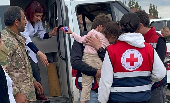 Voksne bærer ut barn av en bil og blir tatt imot av Røde Kors