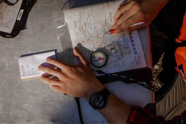 En person står over et kart og kompass