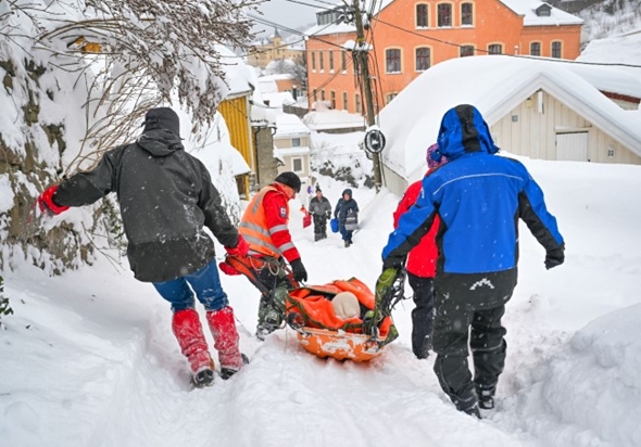 En blind dame blir båret ut av et hus av frivillige i Røde Kors etter at hun ble snødd inne.