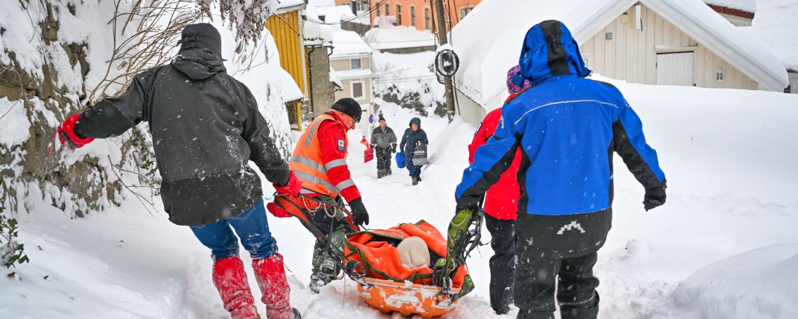 Frivillige mannskaper transporterer pasient i båre