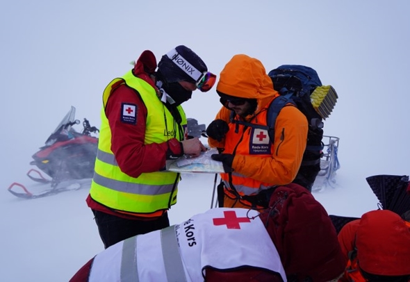 tre frivillige fra Røde Kors trener ute i snøstorm på navigering, søk- og redning.