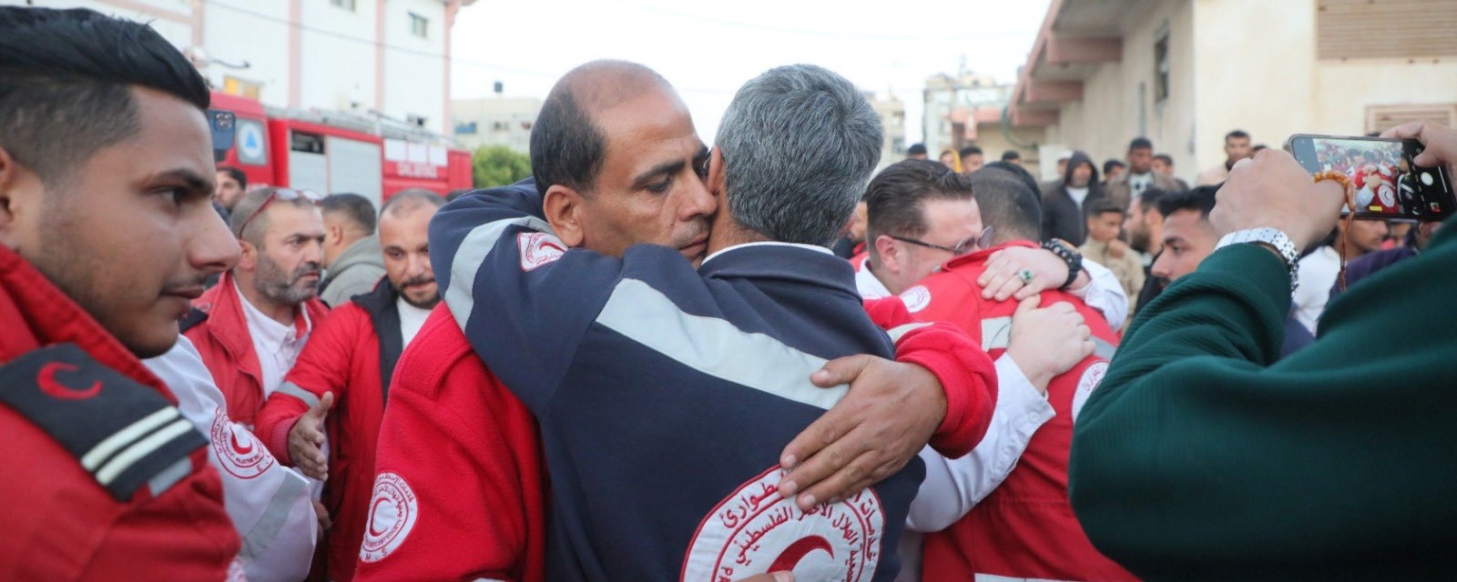 To menn omfavner hverandre ute på gata etter tap av åtte kollegaer. 