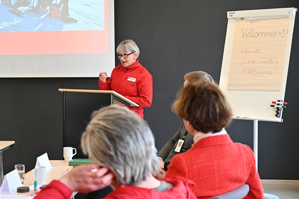 Kvinne snakker til en forsamling med en presentasjon.