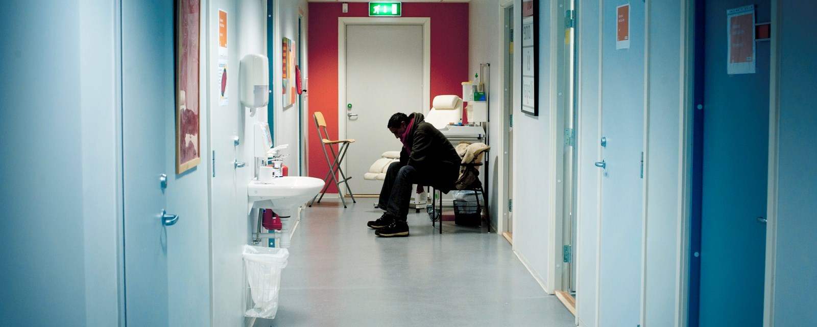 En mann sitter i en korridor og venter på behandling