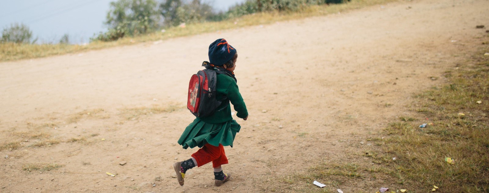 En liten jente løper bortover en grusvei.