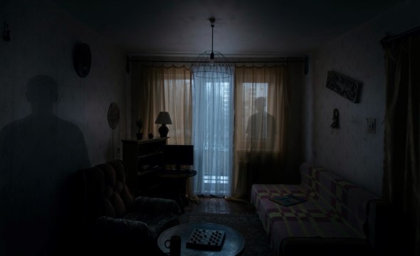 En mørk stue med skugge av en person foran vinduet