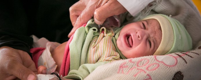 En liten gråtende baby undersøkes av lege