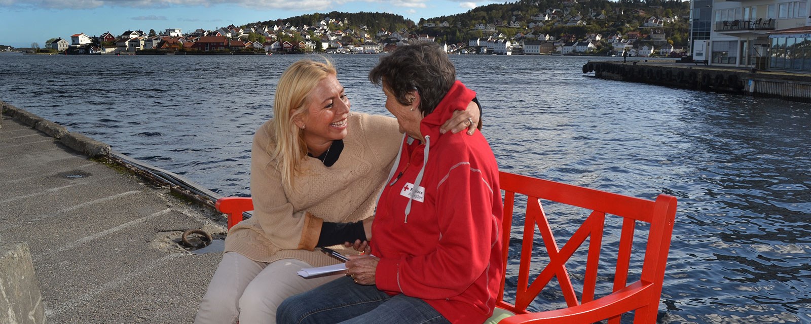 Hisøy Røde Kors. To kvinner på rød benk på kaia.