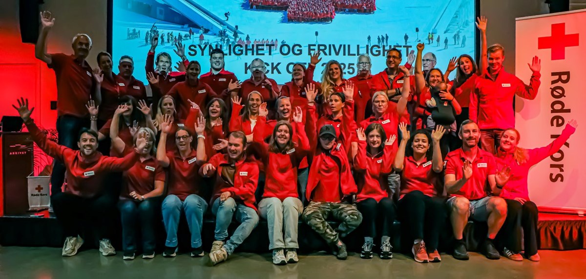 En gruppebilde av alle Røde Kors Kristiansand medlemmene stå på en scene mens de har på seg Røde Kors klærne.