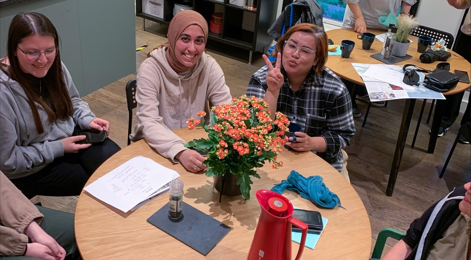 En gruppe med kvinner som koser, de sitter rundt et bord og jobber med et aktivitet.