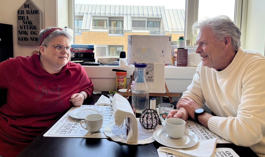 Besøksvert og besøksvenn ved bordet